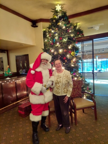 Dorothy, a resident of The Oaks of Pasadena for 12 years (as of 2025), enjoys a visit from Santa