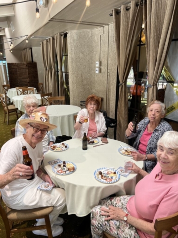 Residents celebrating Oktoberfest at The Oaks of Pasadena senior independent living community, raising glasses and enjoying festive food and drinks