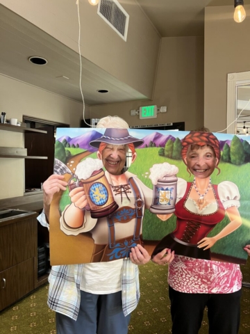 Residents of The Oaks of Pasadena senior living community posing with a festive Oktoberfest photo board during annual celebration