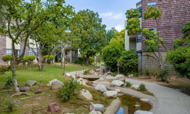 Peaceful stream flowing through The Oaks of Pasadena senior living community, leading to a scenic fish pond surrounded by trees and walking paths — Opened in 1981