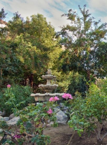 Beautiful fountain surrounded by roses at The Oaks of Pasadena senior living community, offering a peaceful garden retreat for residents