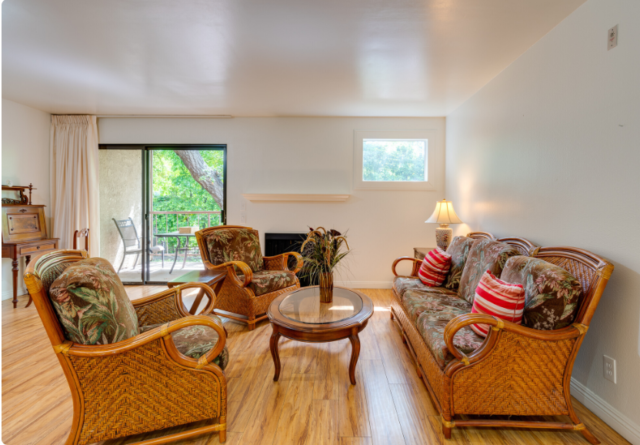 Bright and spacious living room at The Oaks of Pasadena senior apartments, featuring a cozy gas fireplace and large windows for natural light